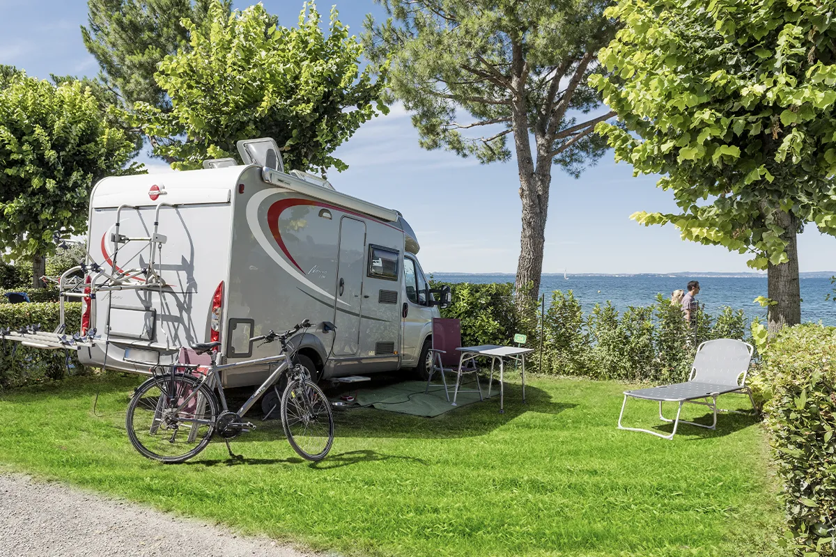 Camper nella piazzola con bicicletta e ampio giardino