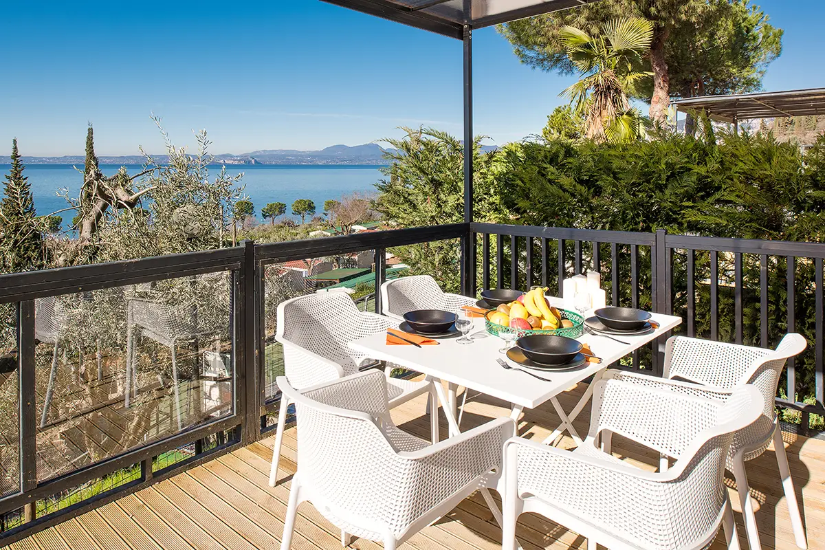 Maxicaravan Aquagarden veranda vista lago con tavola apparecchiata Camping La Rocca